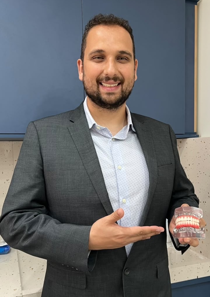 Dr. Germano Vainer Viegas segurando um modelo de prótese sobre implantes