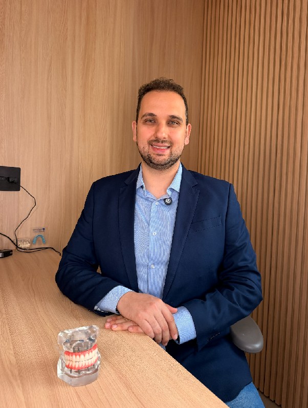 Dr. Germano Vainer Viegas no consultório, com um modelo de prótese total sobre a bancada